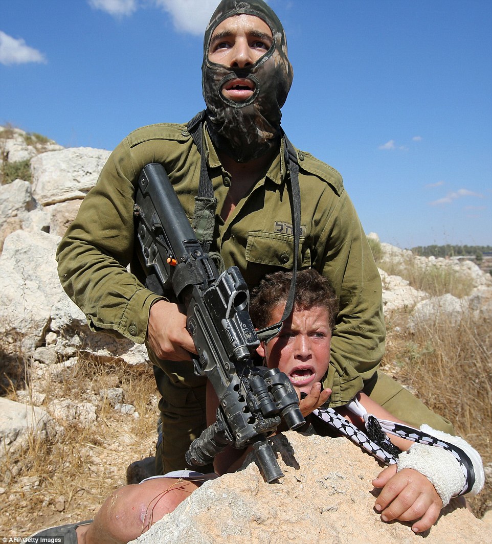 Israeli soldier chokeholds young boy at gunpoint after clashes between Israeli occupation forces and Palestinian protesters following Nabi Saleh  march against illegal Jewish only settlement expansion on their village land. West Bank, Palestine August 28, 2015 (Photo: AFP/Getty )